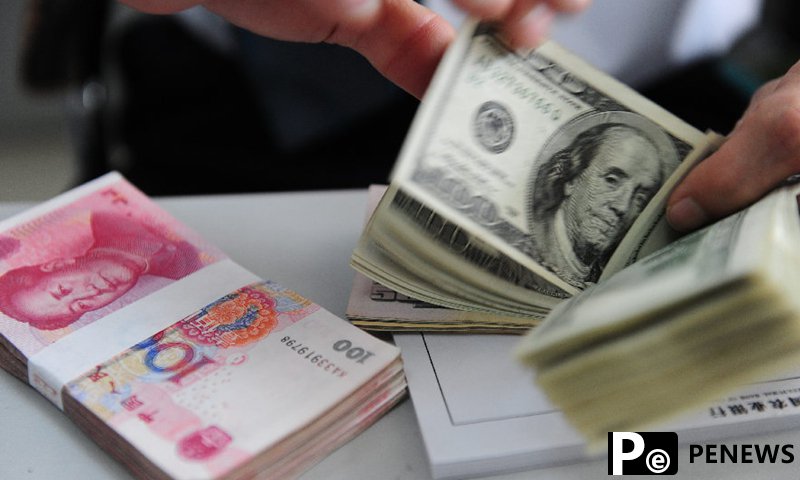 A teller counts U.S. dollar bills at a bank in Qionghai, south China's Hainan Province.Photo:Xinhua